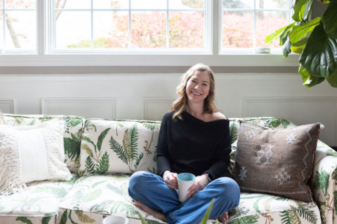 woman in black shirt on floral couch with coffee