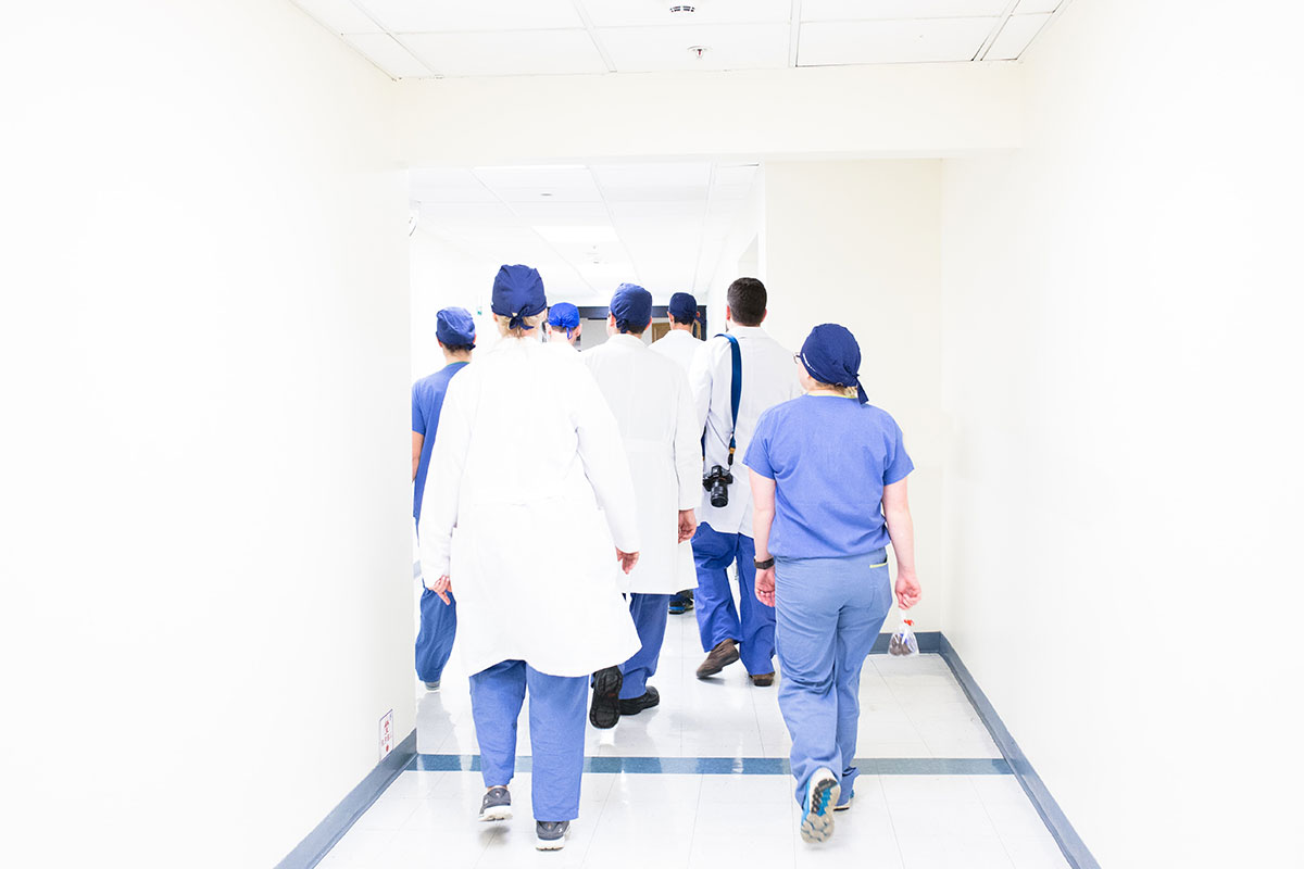 doctors in white and blue scrubs walking down hallway