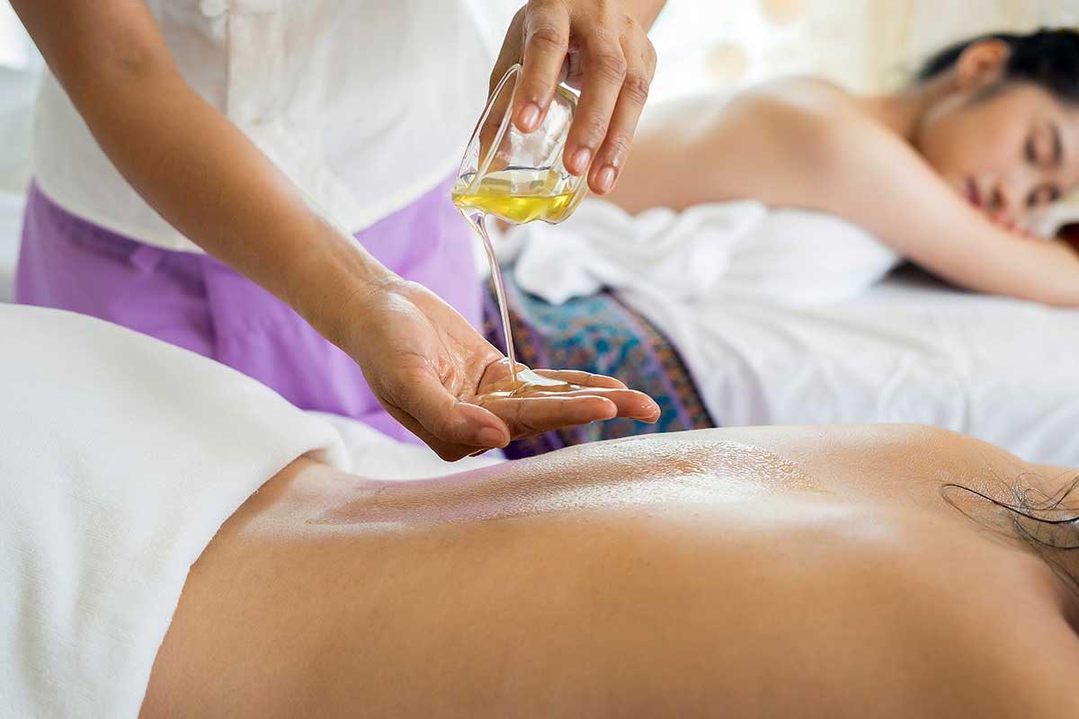 woman pouring oil for back massage
