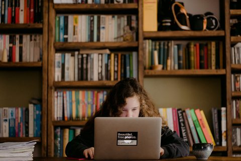 girl working on laptop in home library