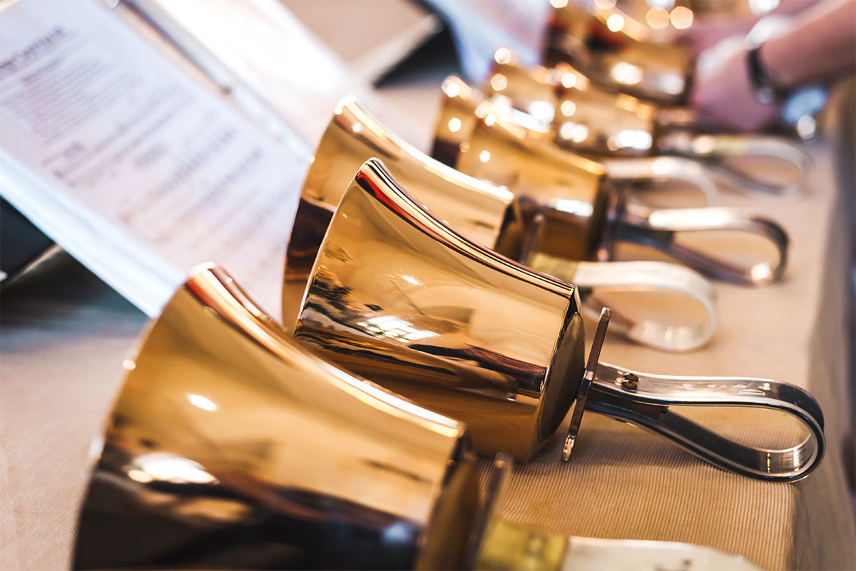gold handbells lined up near sheet music