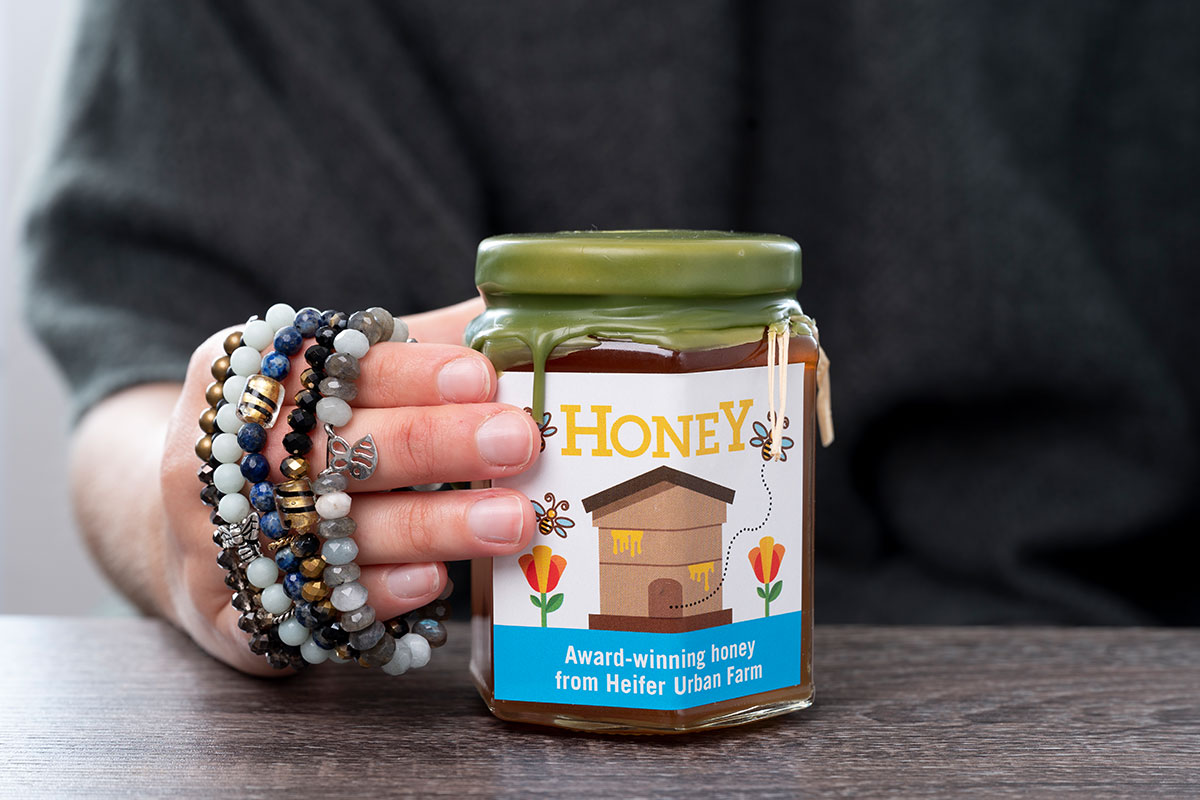 jar of honey held by a hand with bracelets