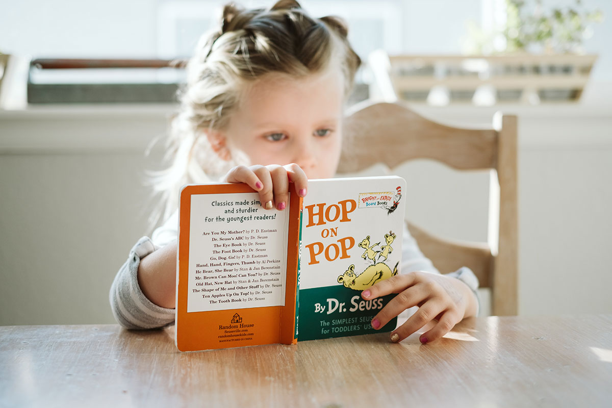 little girl reading hop on pop by dr. seuss