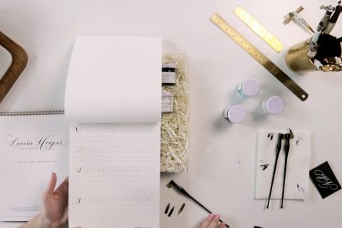 person at desk writing calligraphy