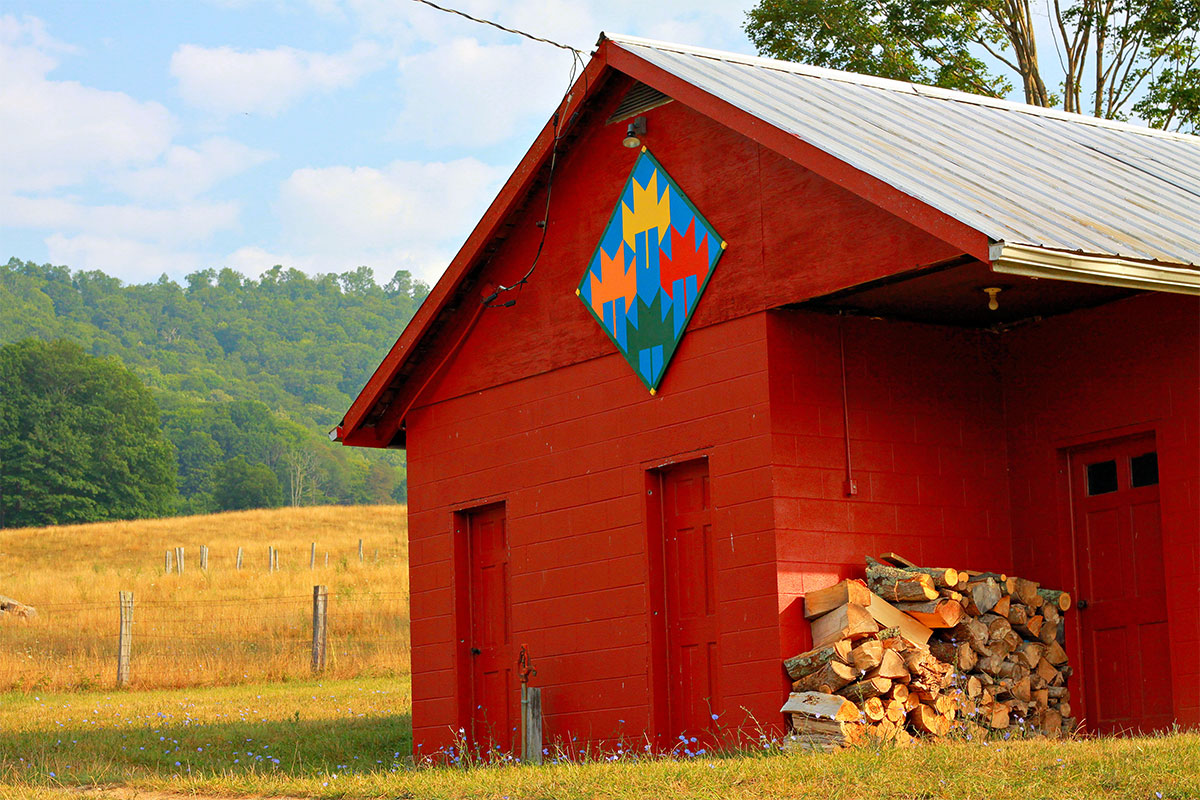 bright red barn with barn quilt on side and blue sky