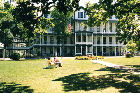 white old house with trees and large lawn with green grass