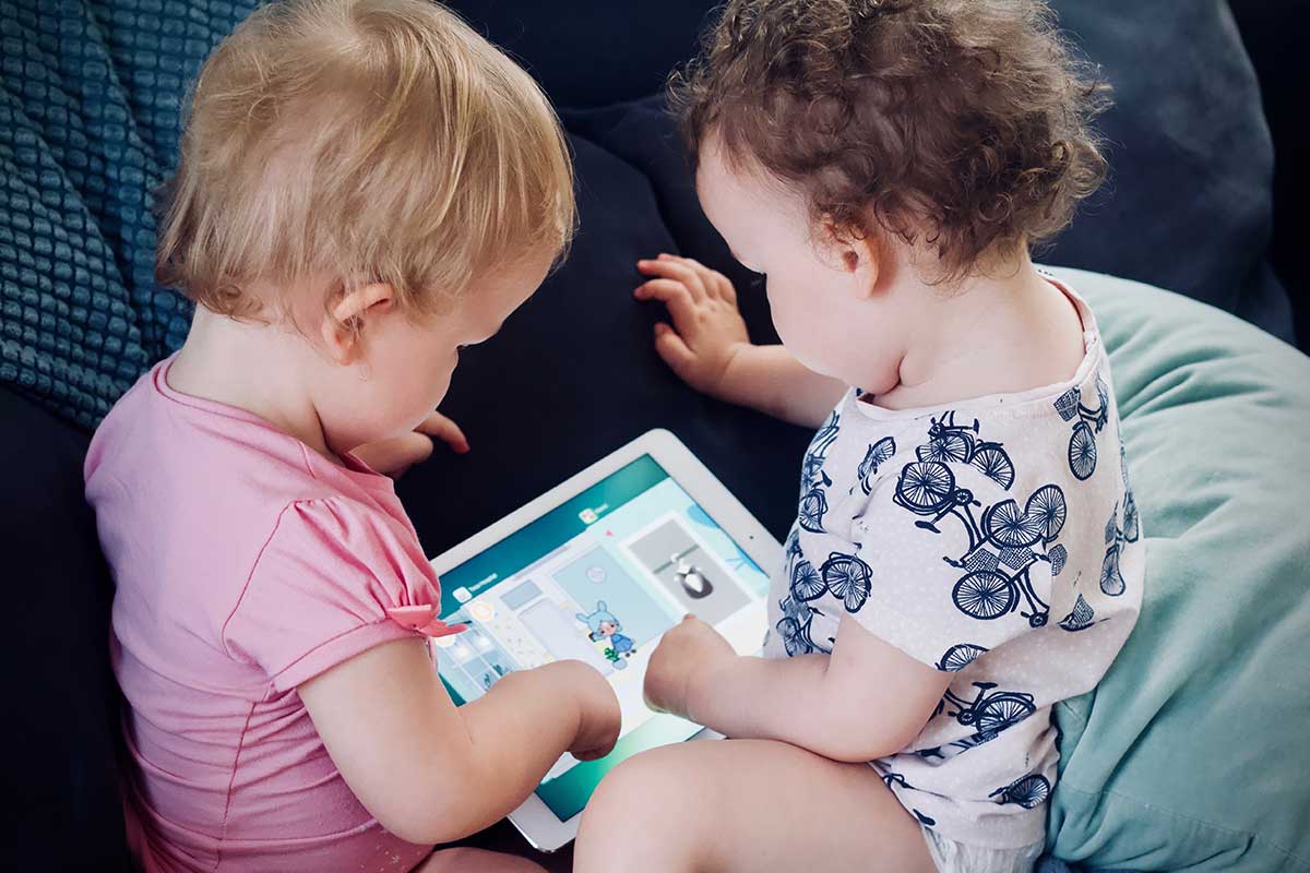 two babies looking at a tablet