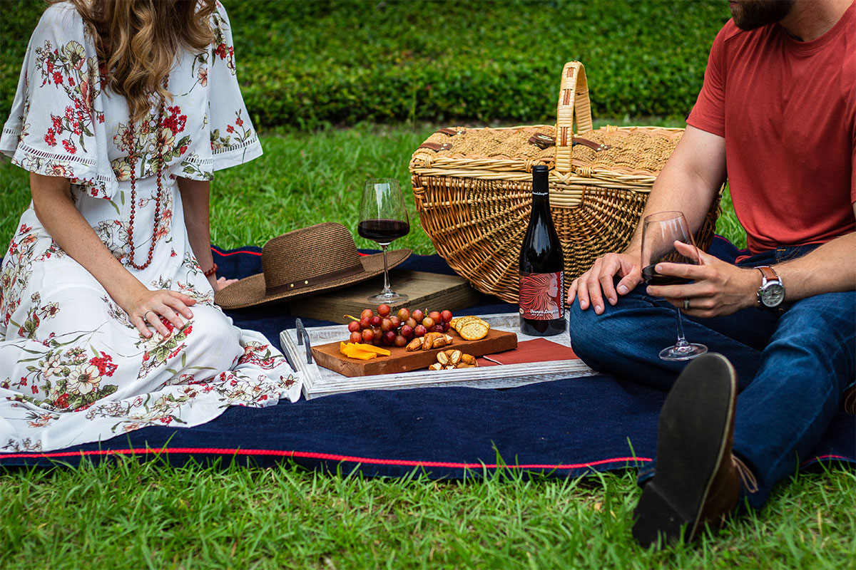 couple sitting on ground with picnic items