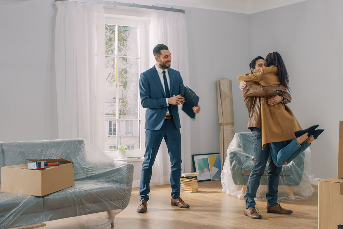 couple hugging in front of real estate agent