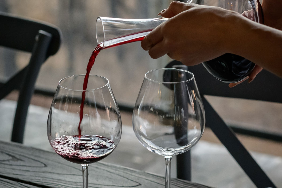 red wine being poured from decanter into two wine glasses