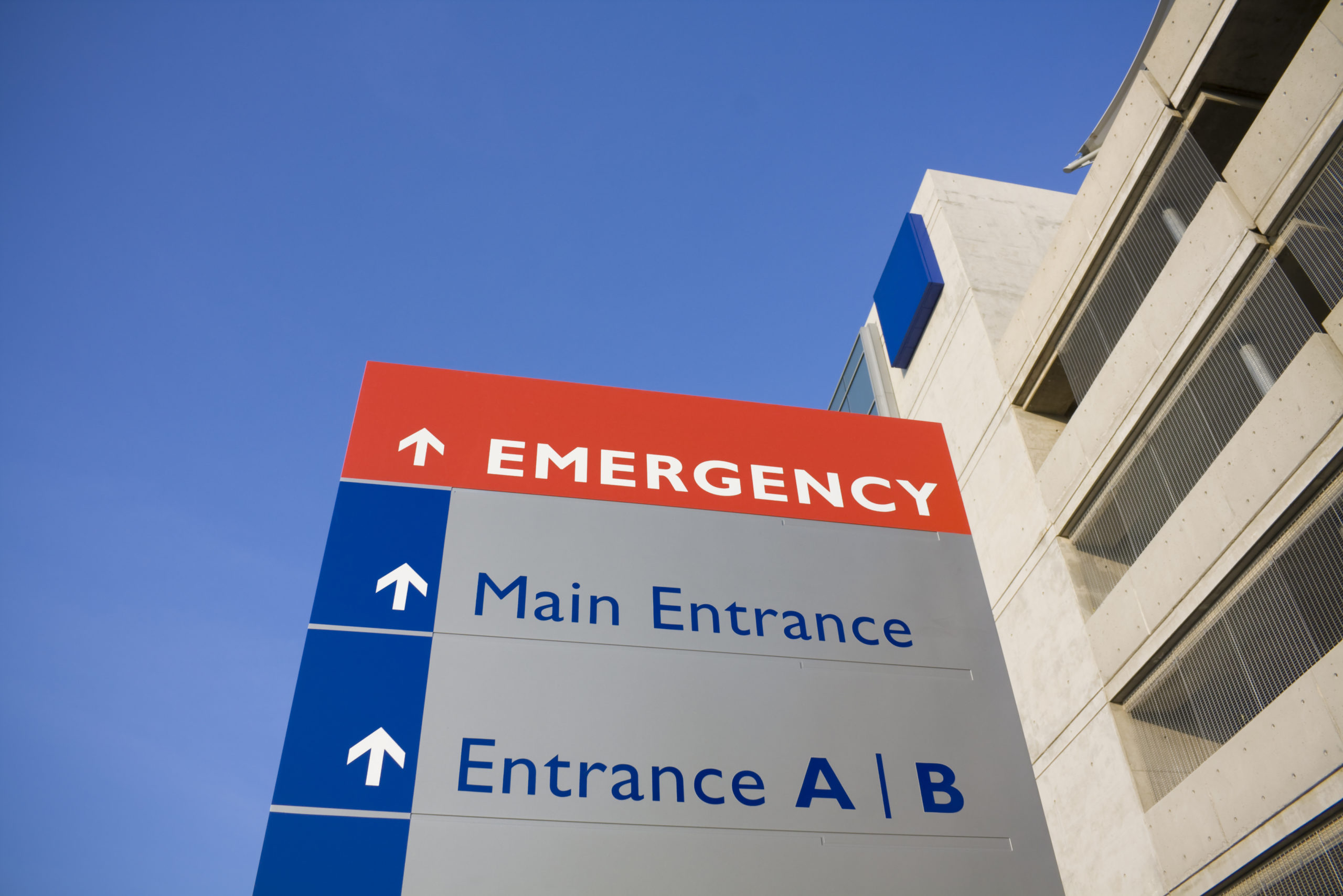 hospital sign with blue sky in background red emergency and main entrance