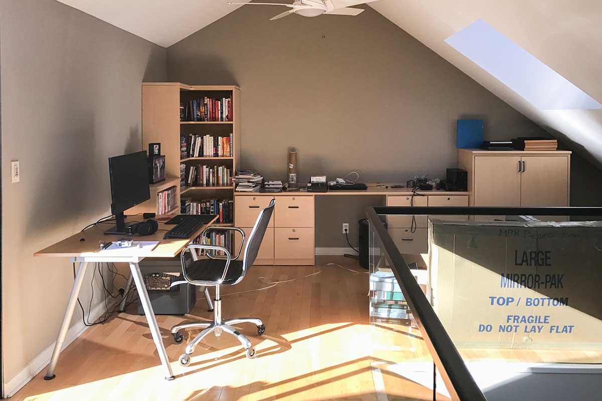 work from home office with wooden shelves and desk and black chair