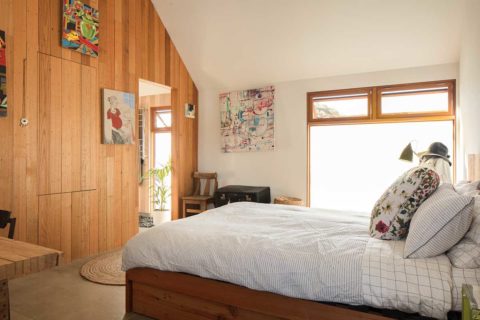 airbnb bedroom with white comforter and wood paneled wall