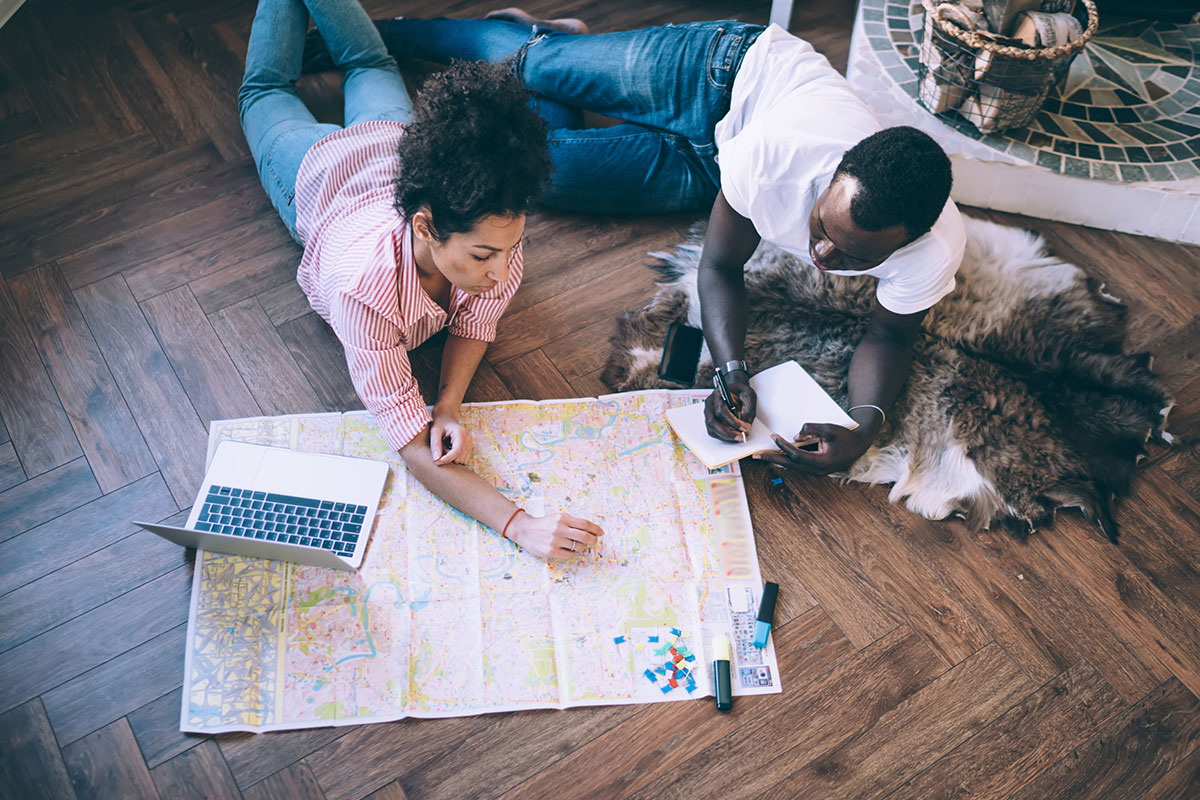 couple on floor in front of map planning trip