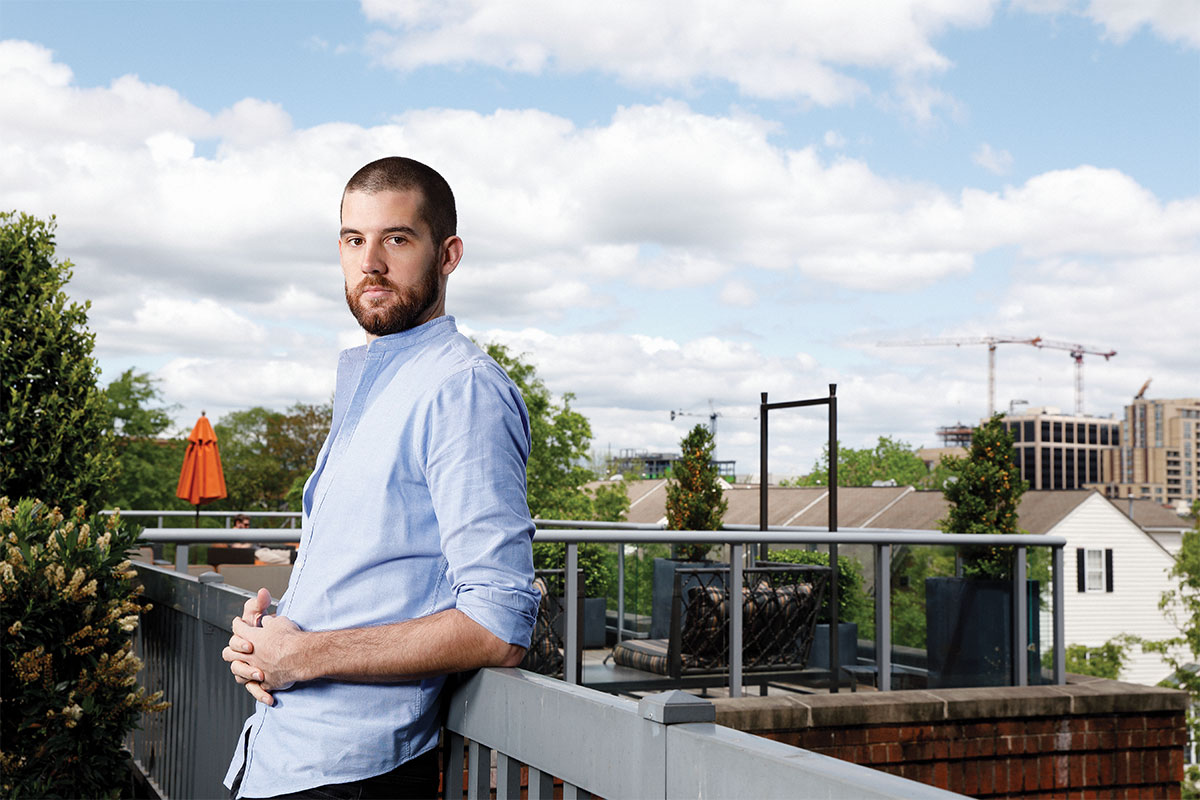 man leaning on railing with blue sky behind him