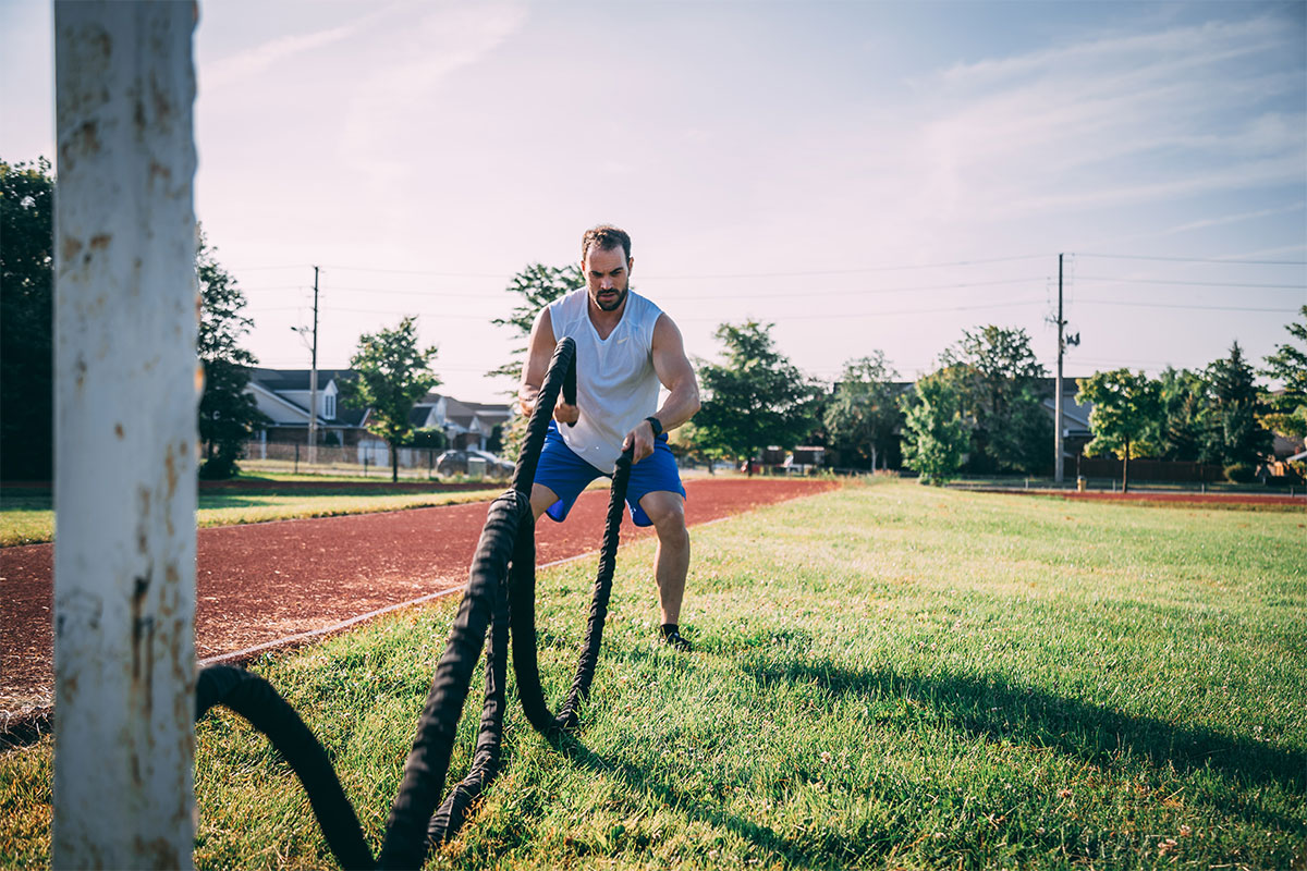 man working out outside with ropes