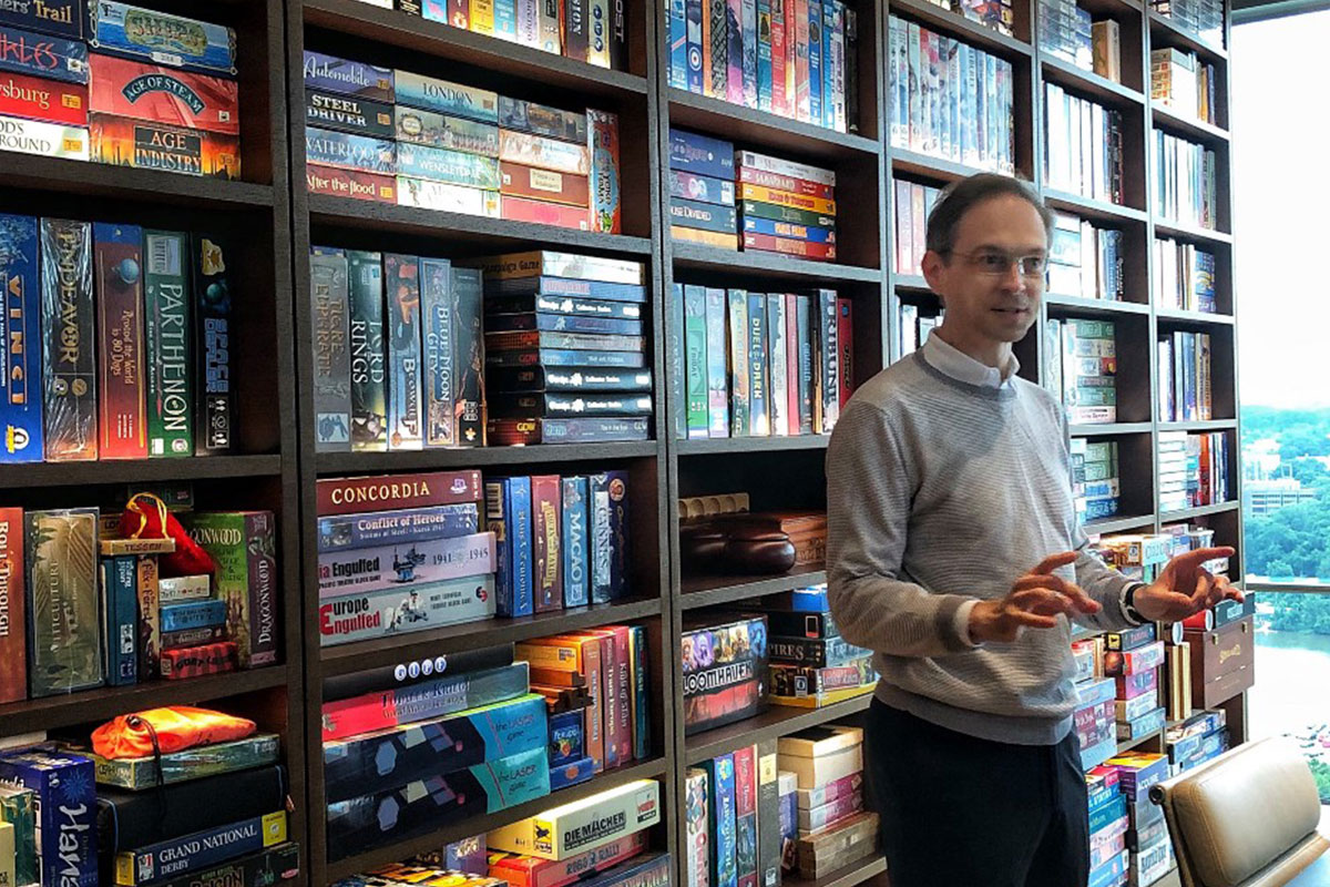 matt calkins in front of a bookcase stacked with board games