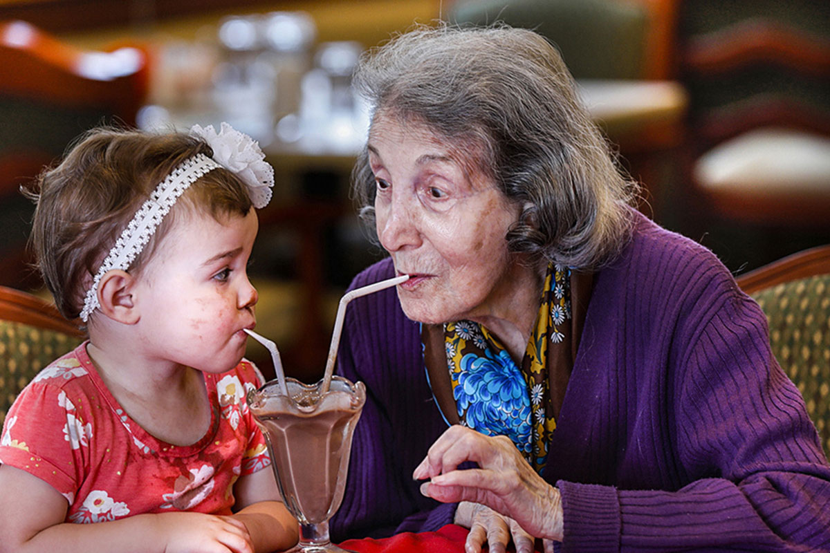 older woman and toddler sharing a milkshake