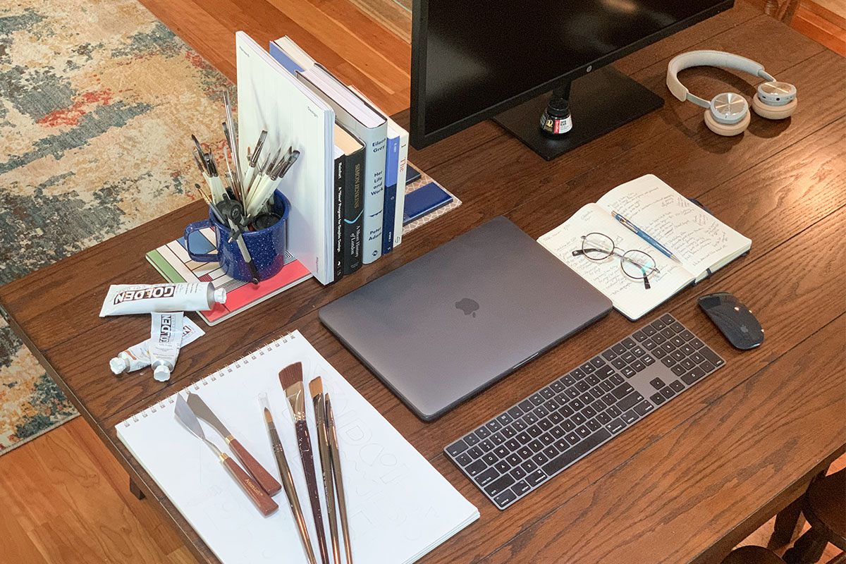Nathan Hill's desk with computer, paint brush and books