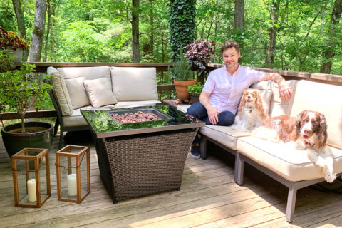 man in purple shit sitting with dogs on outdoor patio