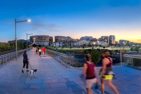 people walking across a bridge in arlington at sunset