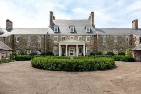 stone grand manor house with large green area and driveway