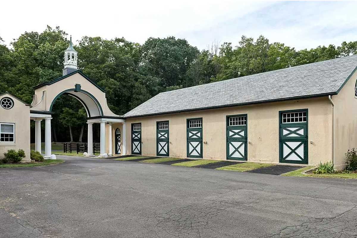 white and yellow horse stables with green doors