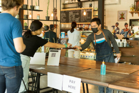 person taking credit card behind table with mask in restaurant