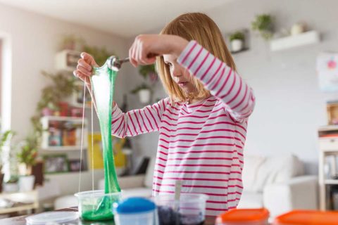 little girl in pink striped shirt playing with slime