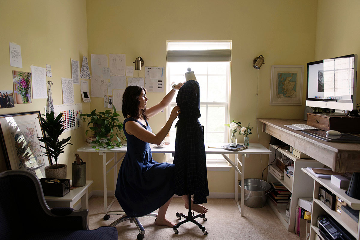 Rebekah Murray making a dress in her yellow studio with a window behind her