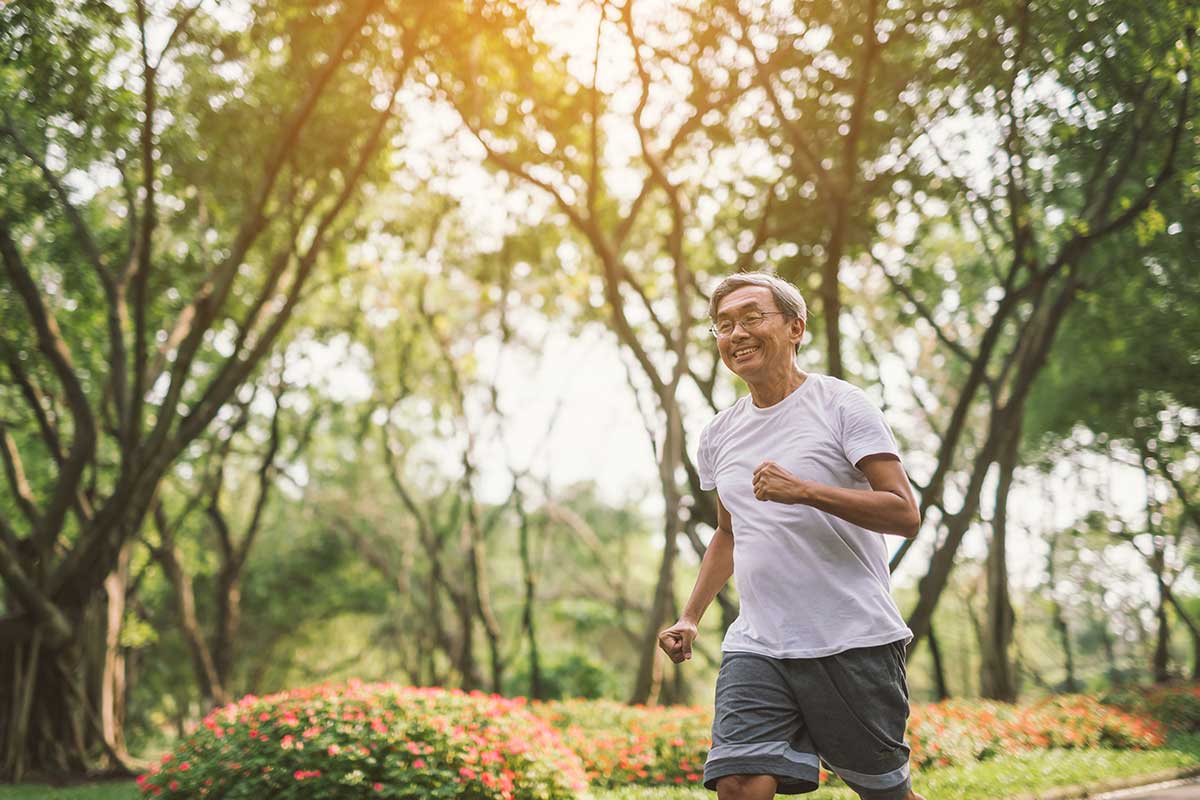 man running outside in trees with sunlight and white t-shirt