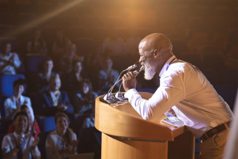 black man speaking on stage in front of audience