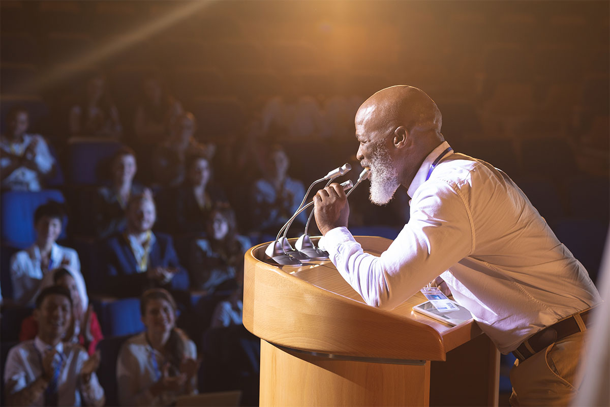black man speaking on stage in front of audience
