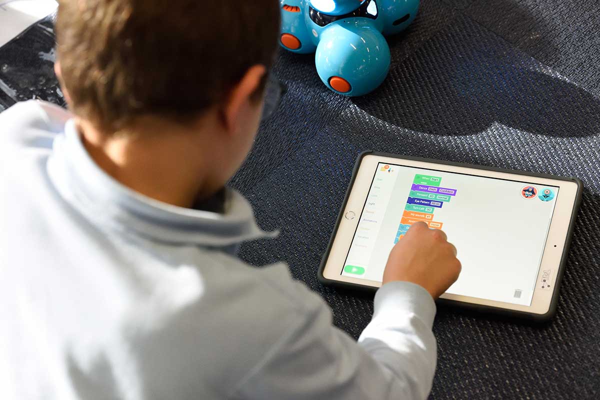 child sitting on tablet with blue toys nearby