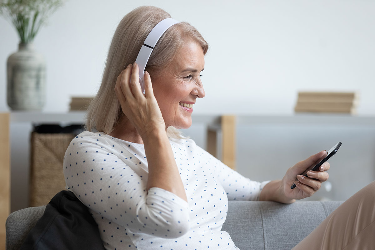 older woman in white shirt listening to headphones