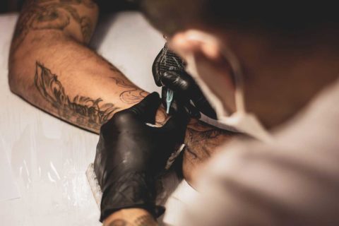 tattoo artist with black gloves and tattooed arm