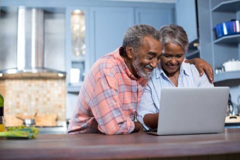 couple looking at laptop in kitchen with plaid shirt