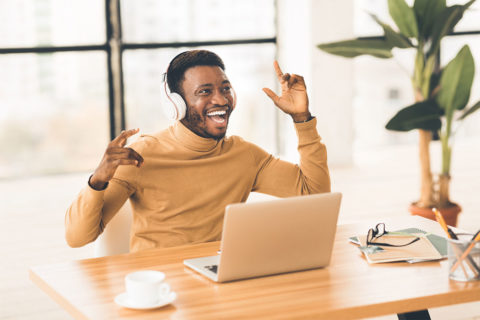 black man in turtleneck listening to music on laptop
