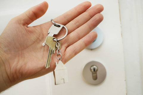 hand holding house keys in front of door