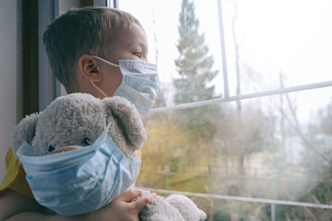 kid and stuffed animal with masks looking out windnow
