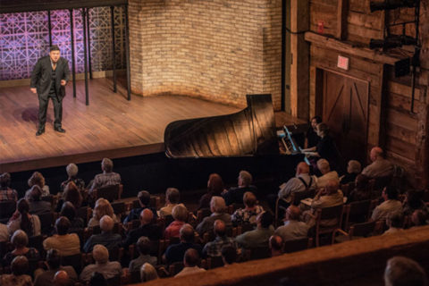 man singing opera on stage to audience