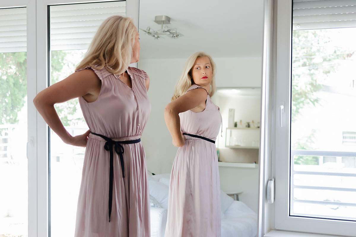 woman in pink dress looking in the mirror