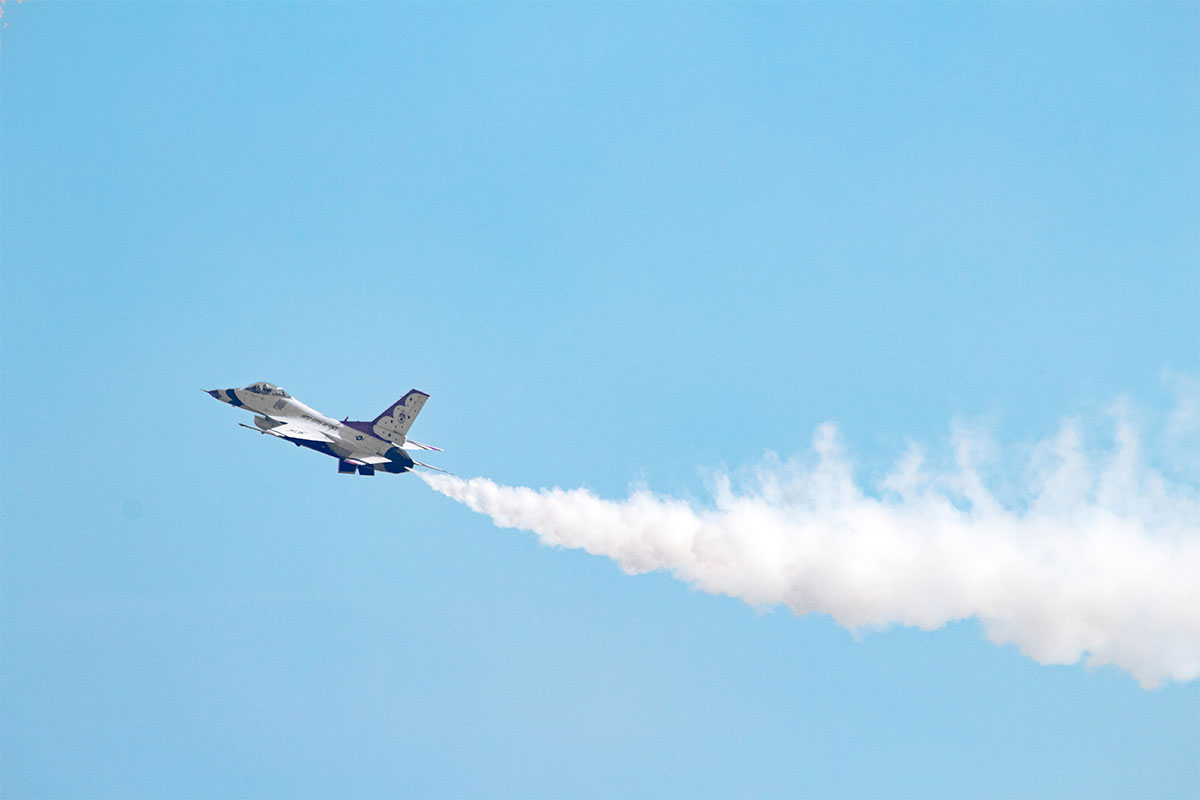 airplane in sky with jetfuel smoking behind it