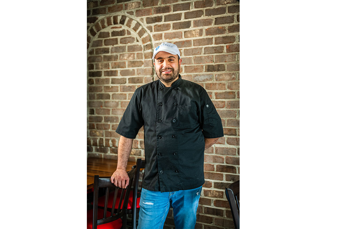 chef smiling in front of brick wall