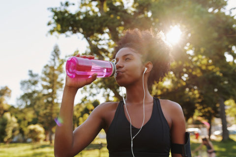 woman drinking from pink water bottle