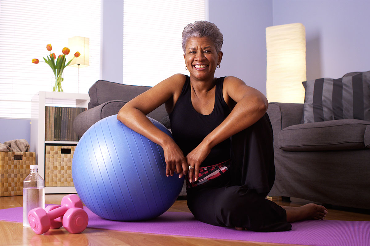older black woman working out in her living room with bosu ball