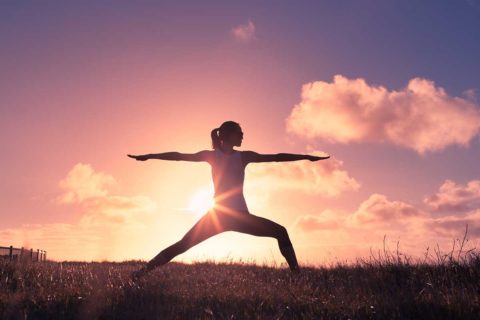 woman doing yoga in front of sunset