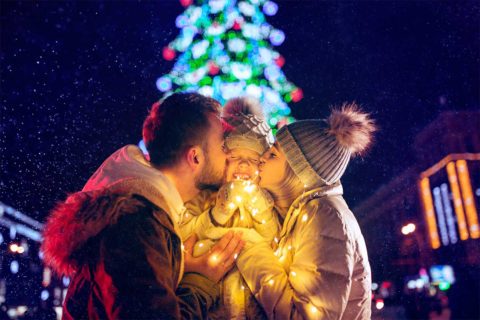family in front of holiday lights