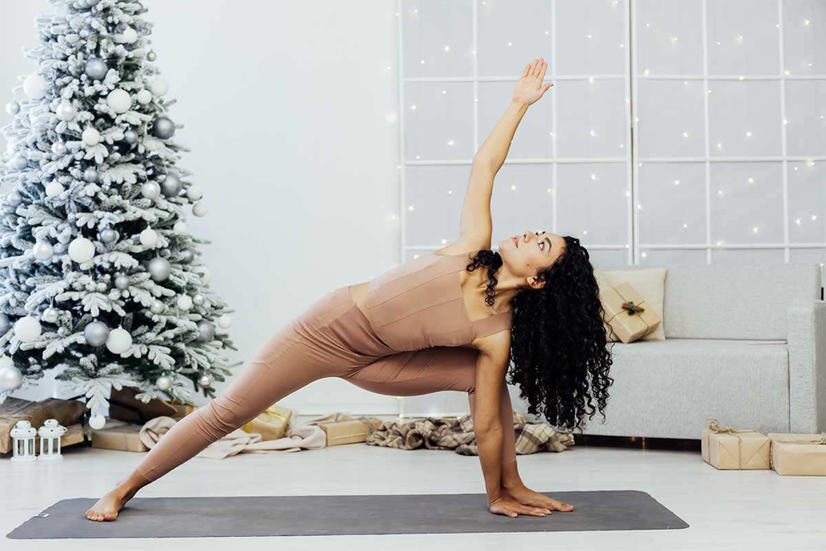 woman doing yoga in front of christmas tree
