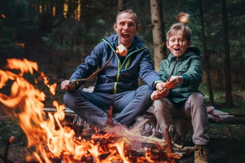 father and son roasting marshmallows on campfire